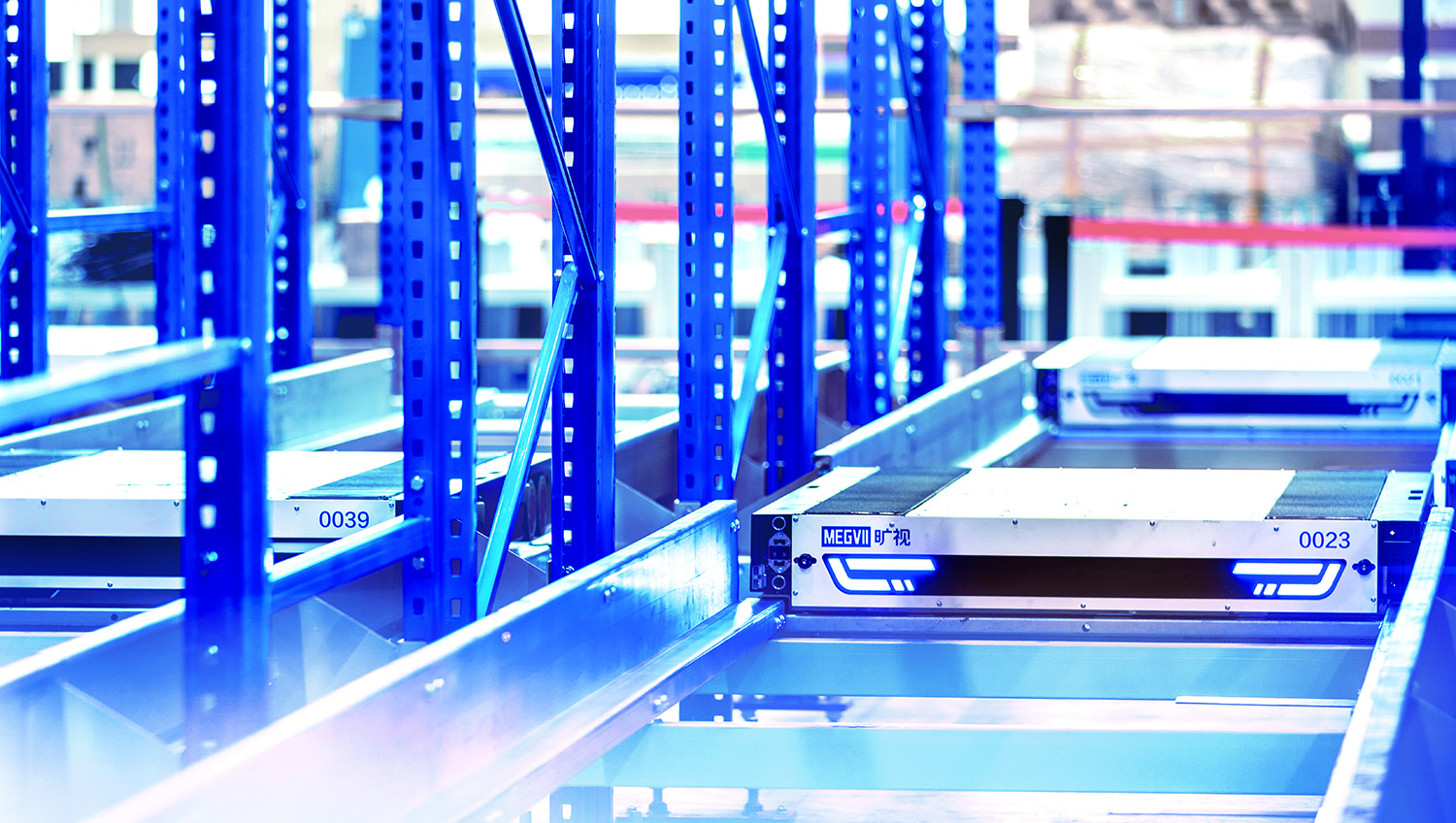 Automated pallet shuttle robots operating on metal racking shelves in a warehouse.