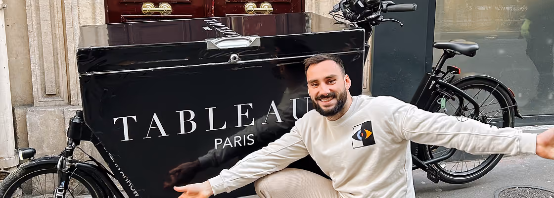 Tom Tarsiguel devant un vélo cargo siglé Tableaux Paris