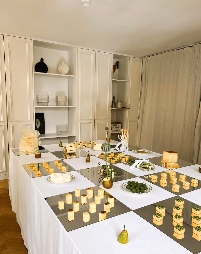 Vue d’ensemble d’une scénographie de buffet cocktail avec pièces signature présentées sur des miroirs