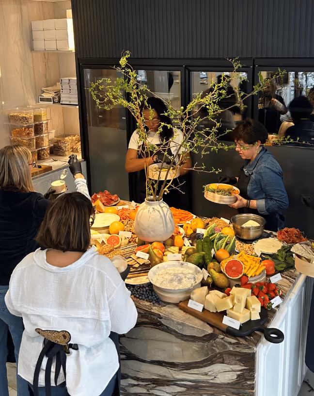 Masterclass Tableaux Paris autour d’un îlot, avec plusieurs participants et les ingrédients pour composer des plateaux