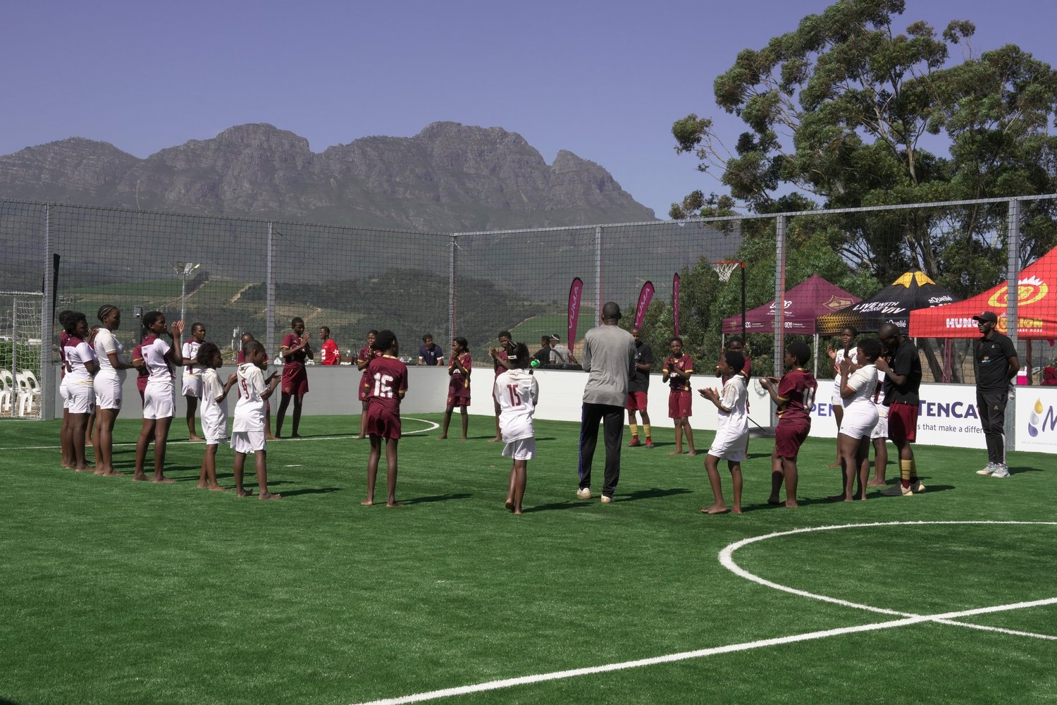 Young people and coaches participating on the Open Play Foundation GreenSource sports field in Kayamandi