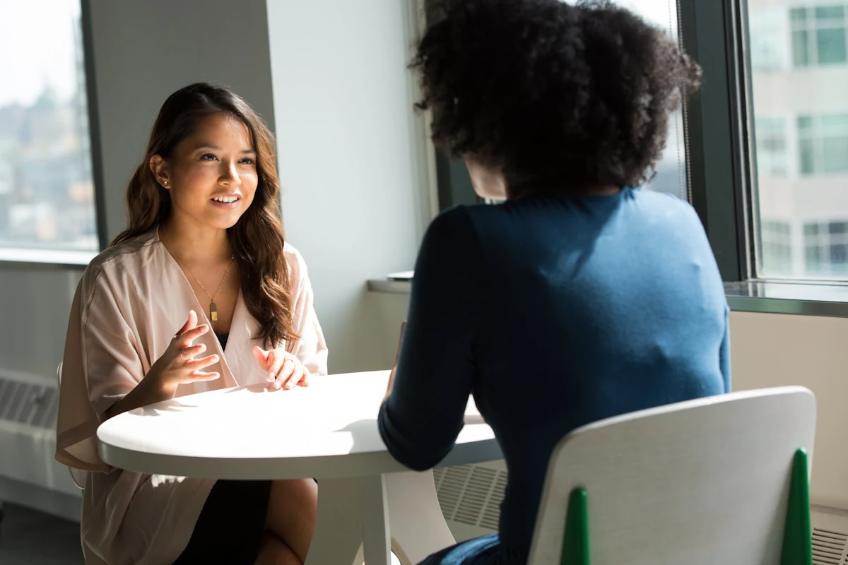 Two people in a quiet face-to-face conversation, representing continuity between a participant and program staff.