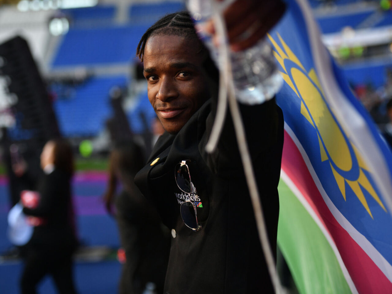 WorldSkills participant at the Lyon 2024 closing ceremony, with a national flag.