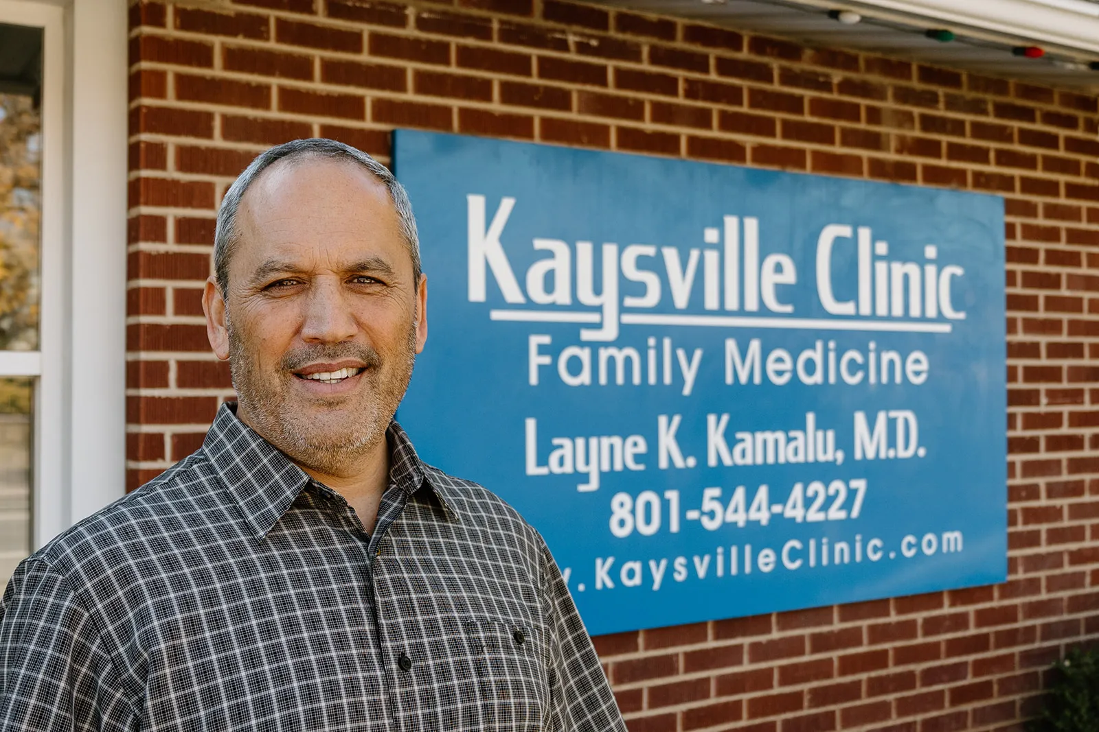 dr kamalu in front of Kaysville Clinic