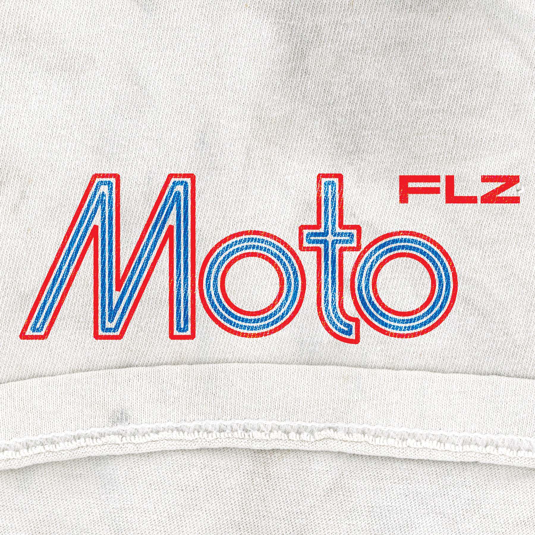 Close-up of a white fabric logo with text 'Moto' in blue outlined red and 'FLZ' in solid red. MotoFeelz logo. 