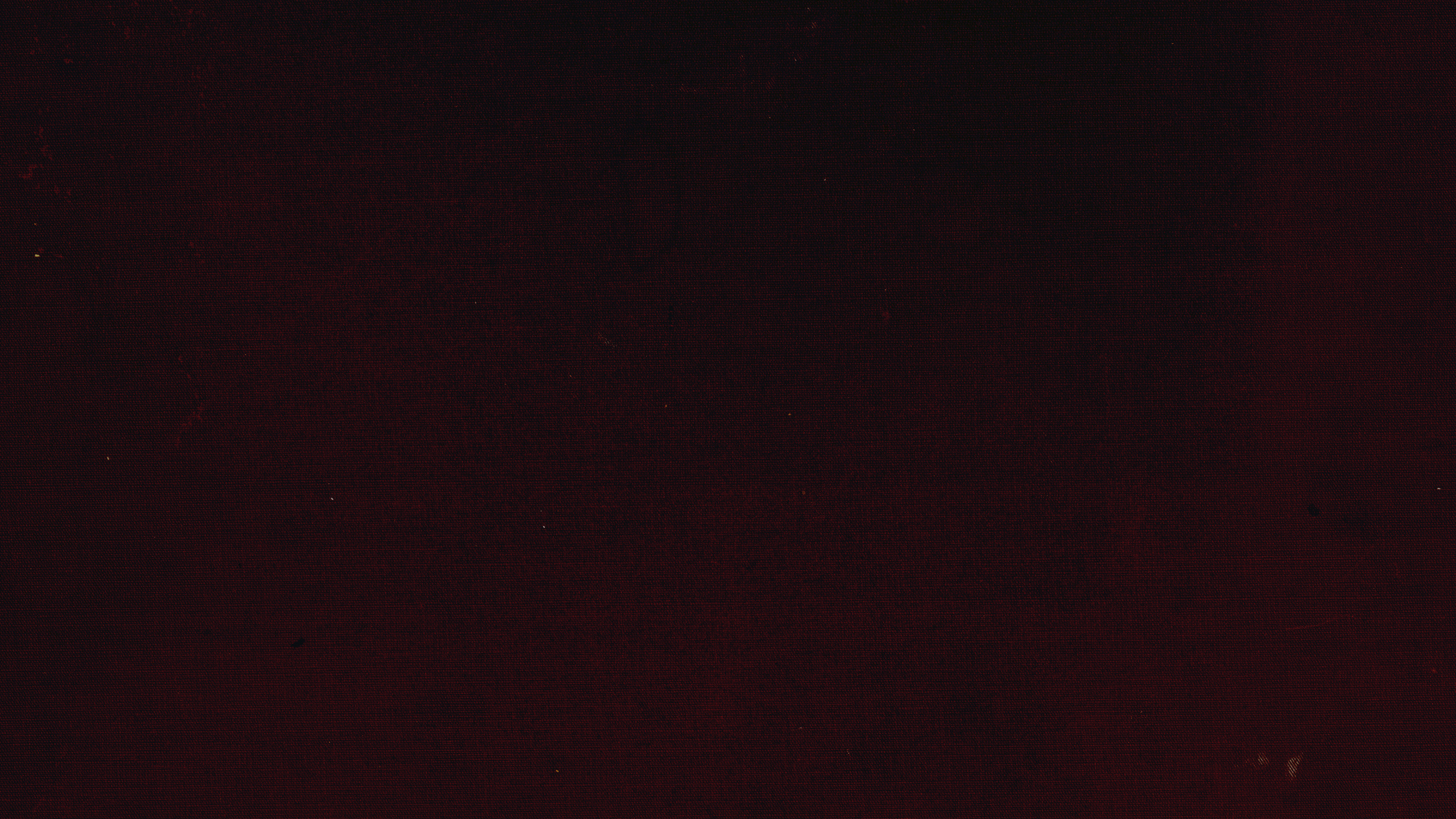 Dark textured surface with subtle reddish and brown tones and faint scratches.