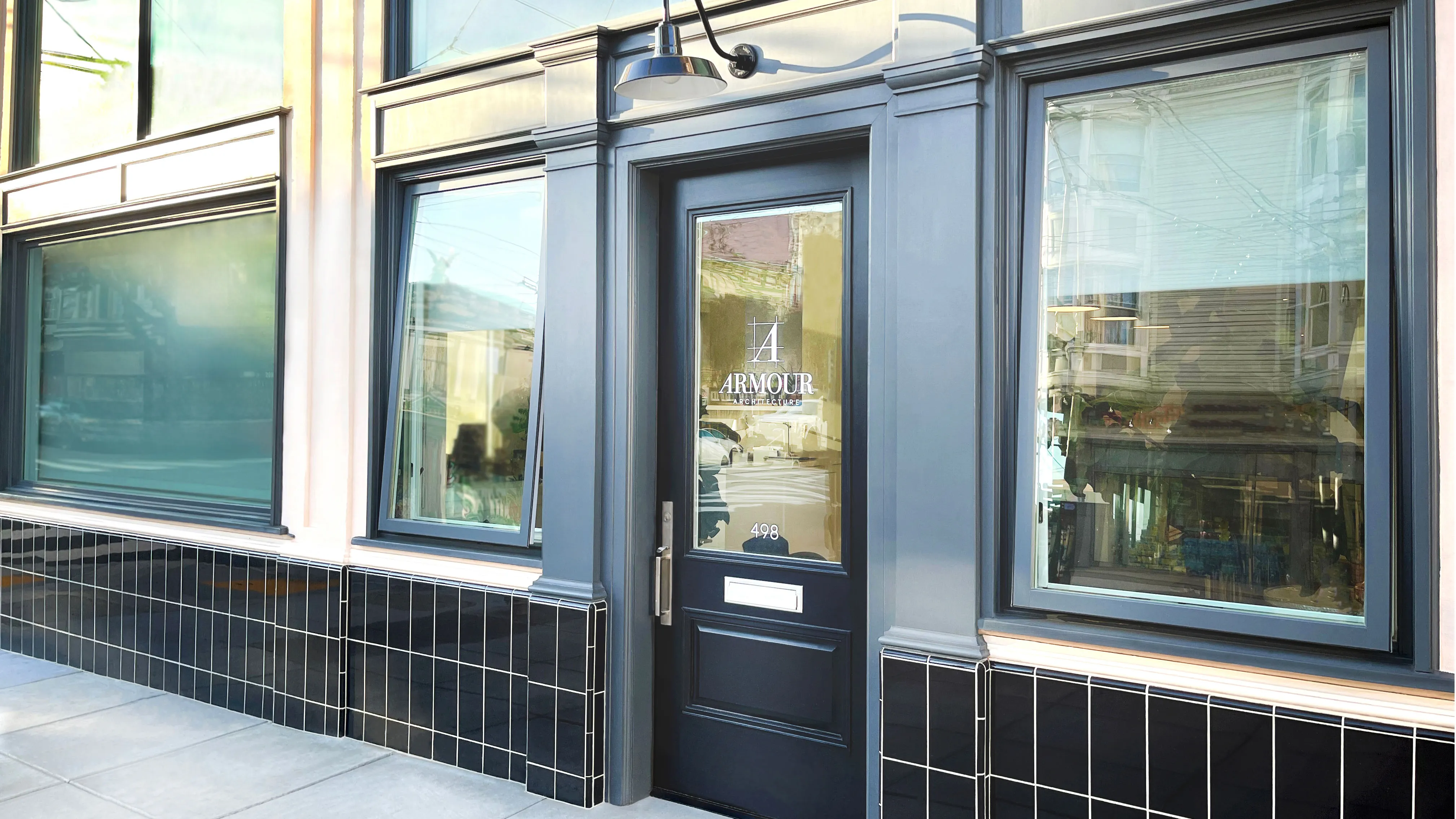 Exterior of Armour Architecture office with black-framed door and large windows on a tiled facade.