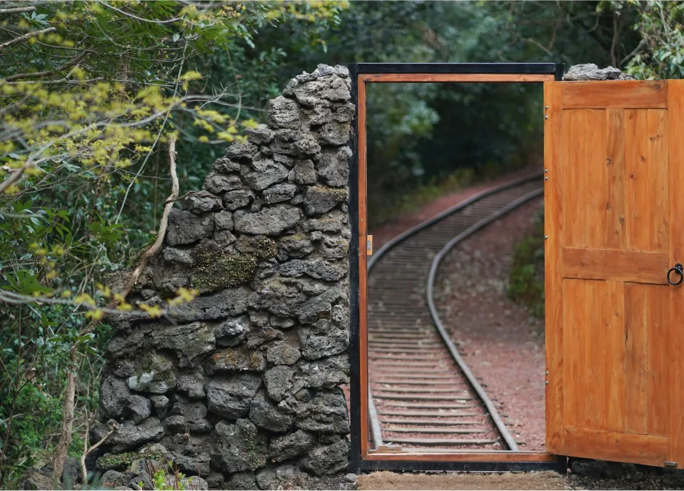 A open door in nature, with a train track going through