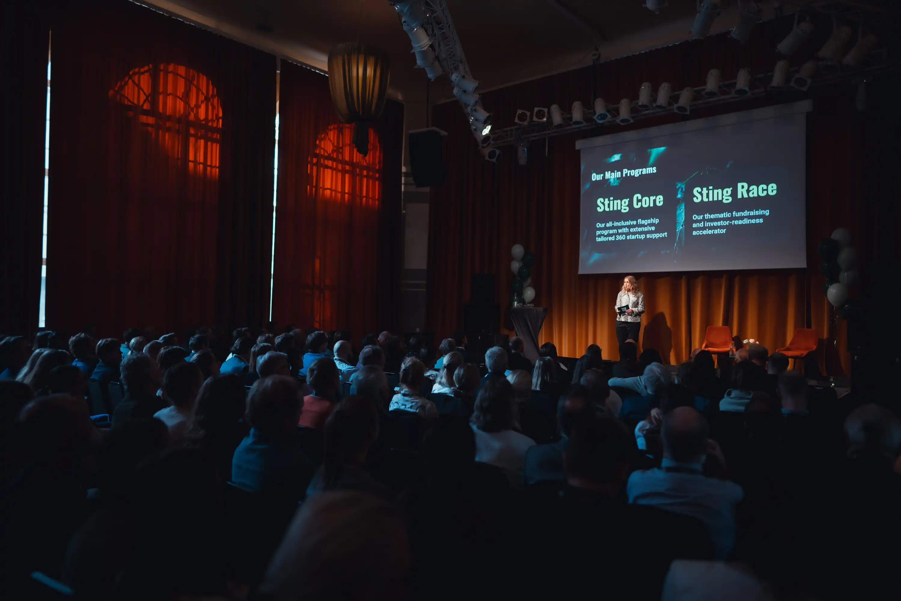 An audience looking at the presenter on stage. 
