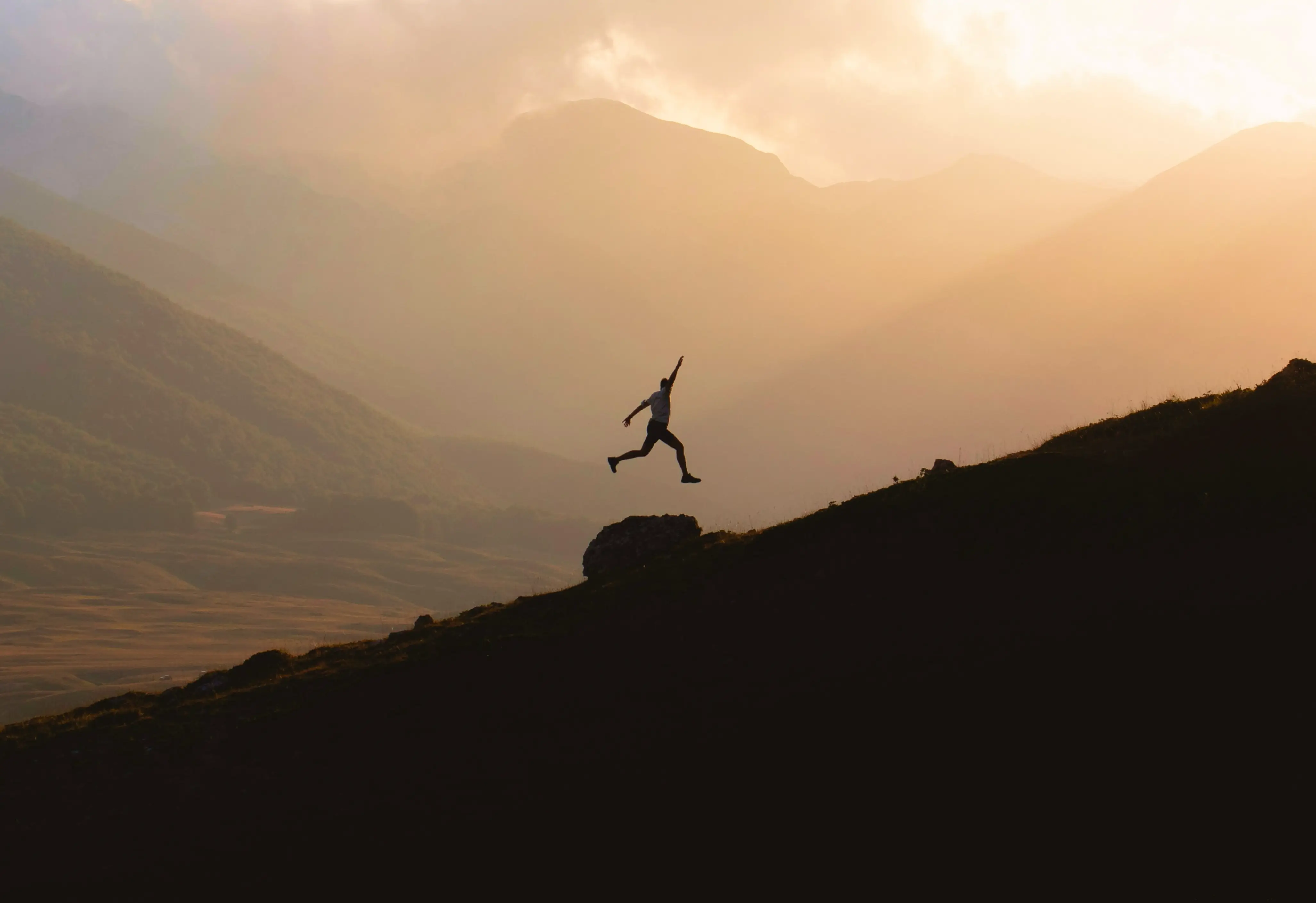 Silhouette of a man jumping in the mountains
