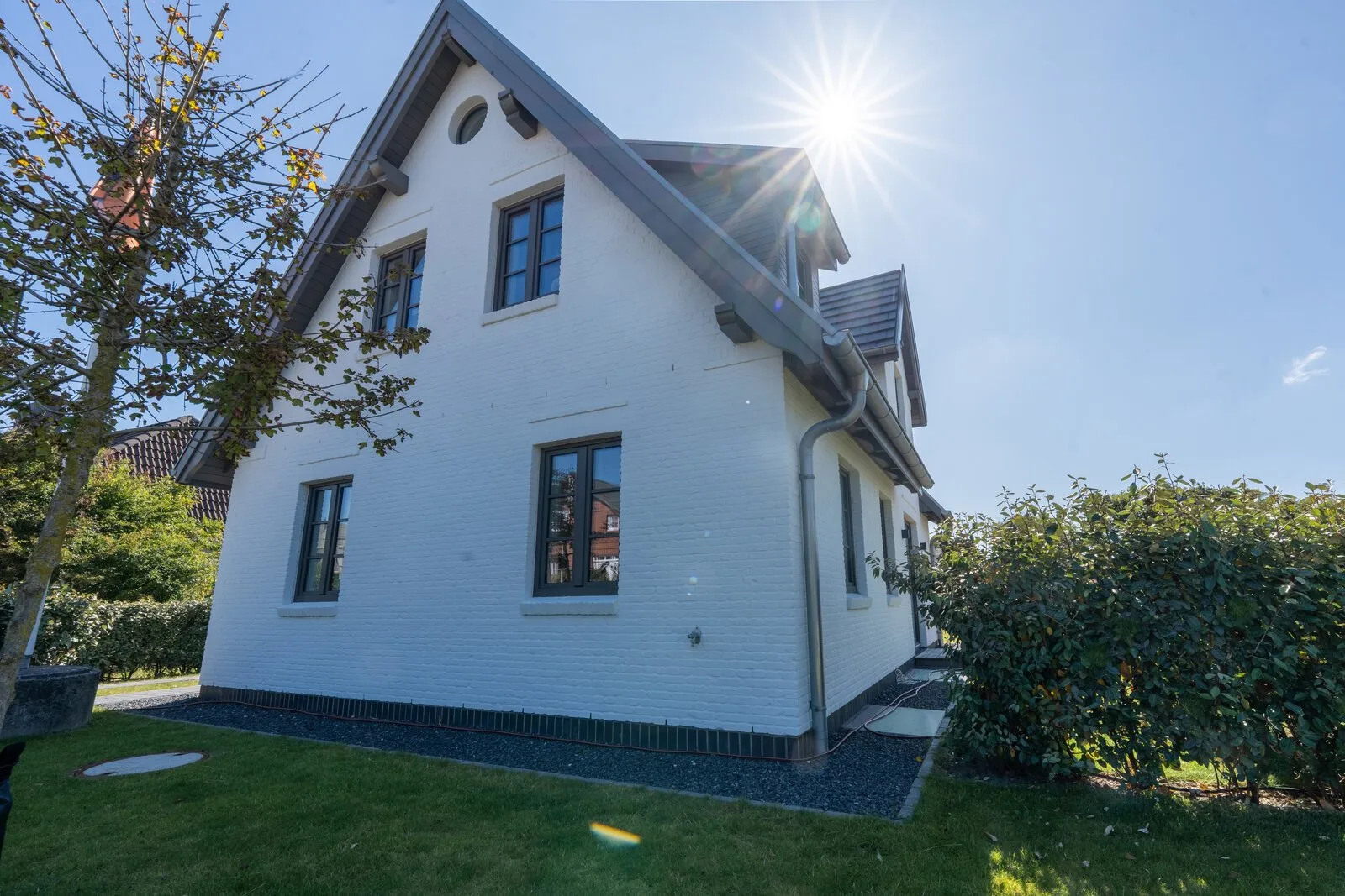 Außenansicht des neu gebauten Friesenhauses mit Backsteinfassade und Satteldach, davor eine Rasenfläche