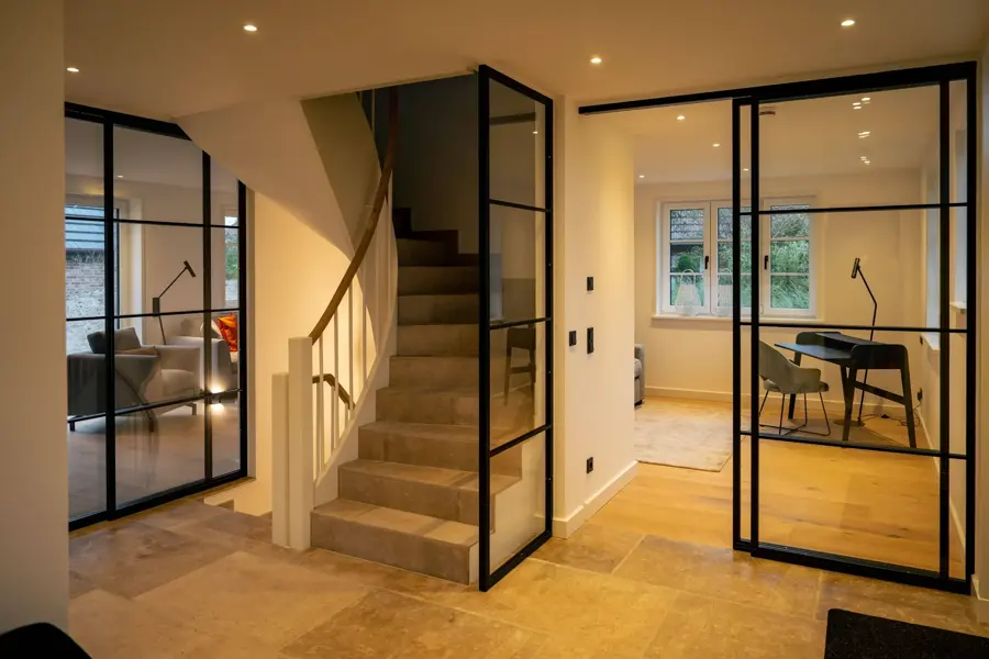 Innenflur mit schwarz gerahmten Sprossen-Glaswänden und Treppe