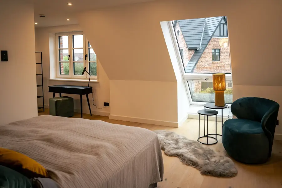 Schlafzimmer unter Dachfenstern mit grünen Sesseln