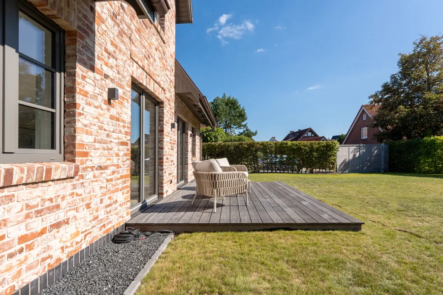 Terrasse mit Loungesesseln an der Backsteinfassade, Blick in den Garten