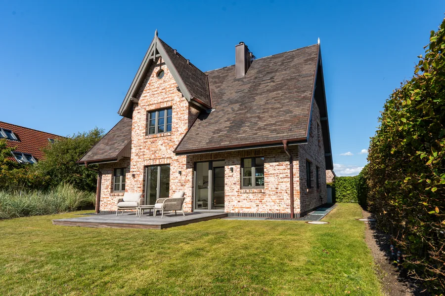 Gartenseite mit Terrasse, Loungemöbeln und Rasen