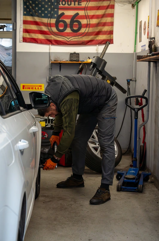 Radnik obavlja servis i zamjenu guma na automobilu u radionici.