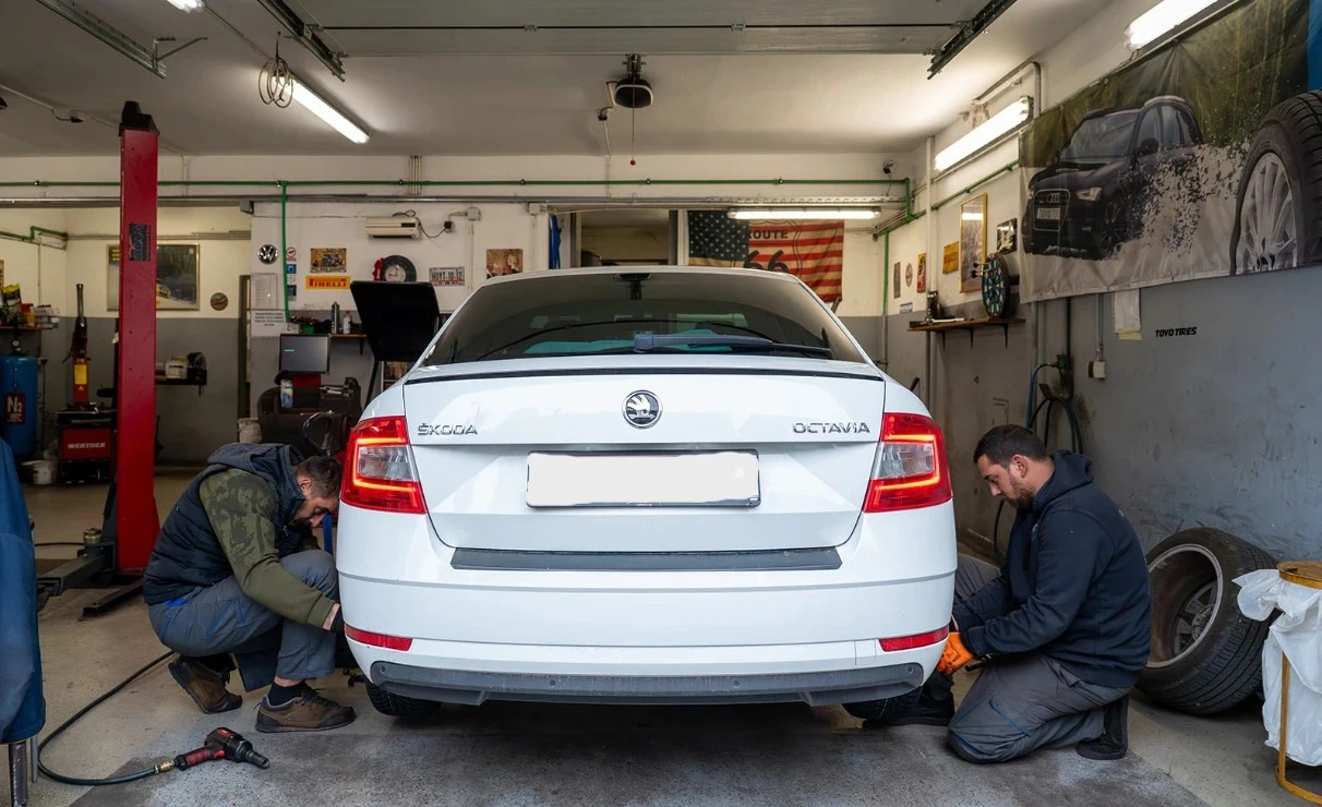 Dvojica radnika obavljaju zamjenu guma na automobilu u vulkanizacijskoj radionici.