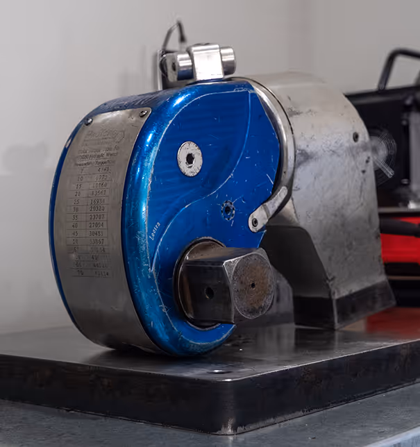 Industrial bolt tensioning equipment with blue housing in professional workshop environment