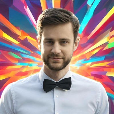 A man with short brown hair and a beard wearing a white shirt and black bow tie, with a colorful abstract burst background.