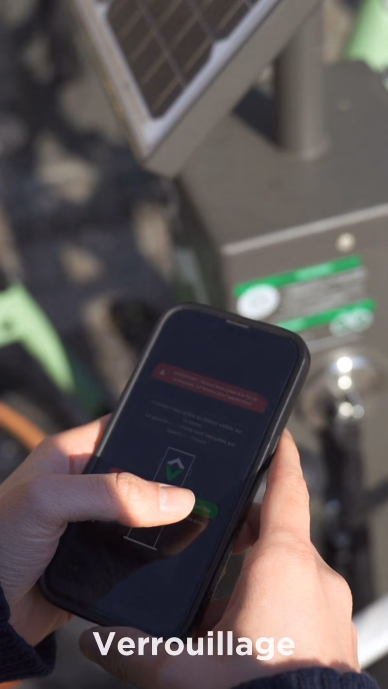 Un cycliste utilise l'application V-Lock devant une borne