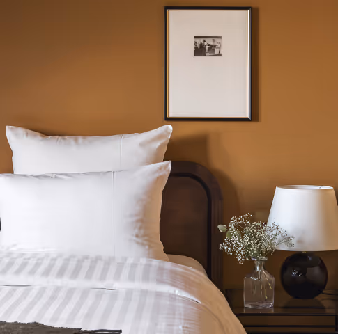 Chambre avec lit et tableau au mur et table de nuit avec fleurs Orso Hotels Paris
