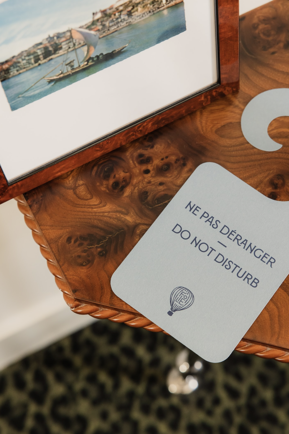 Panneau 'Ne pas déranger / Do not disturb' posé sur une table en bois avec un cadre photo à côté.