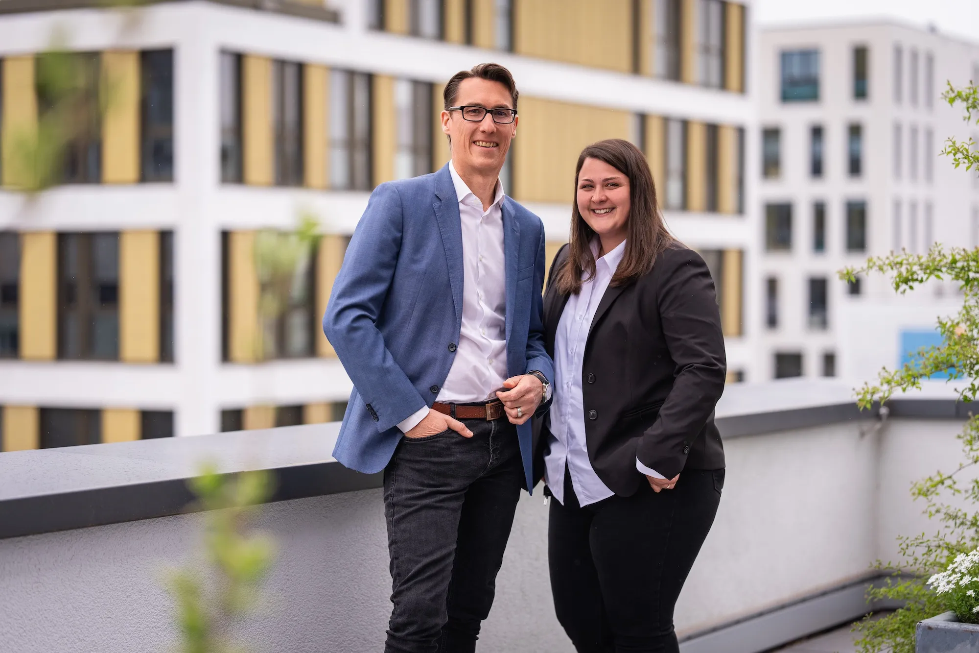 Two of the Adeleon team members in front of an office building