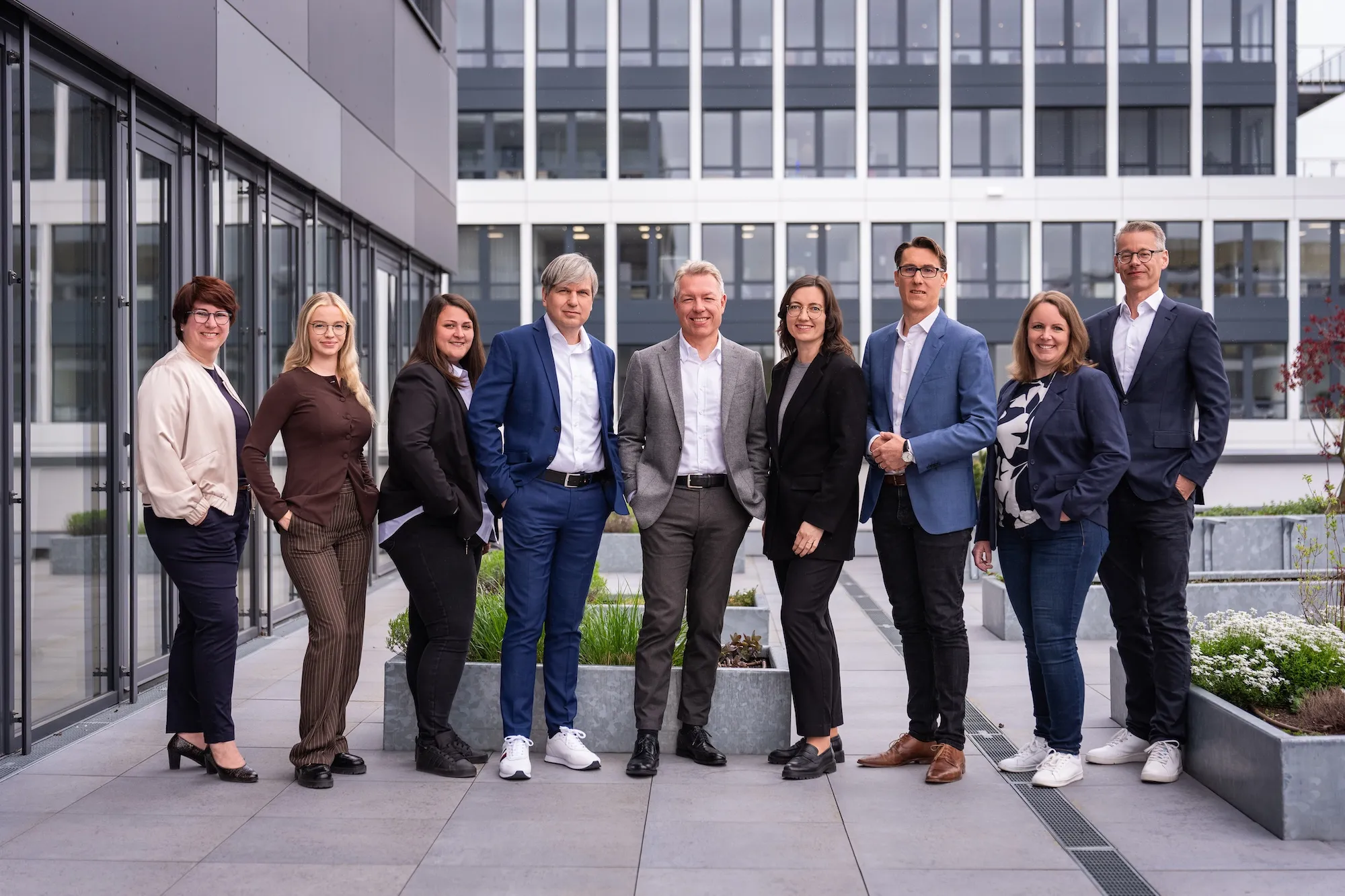 A group photo of the whole Adeleon team in front of an office building