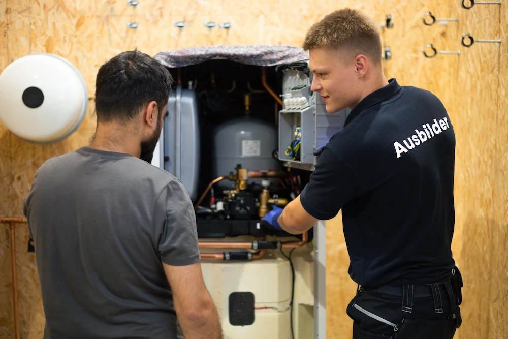 Zwei Mitarbeiter in der Enpal Akademie üben an der Wärmepumpe