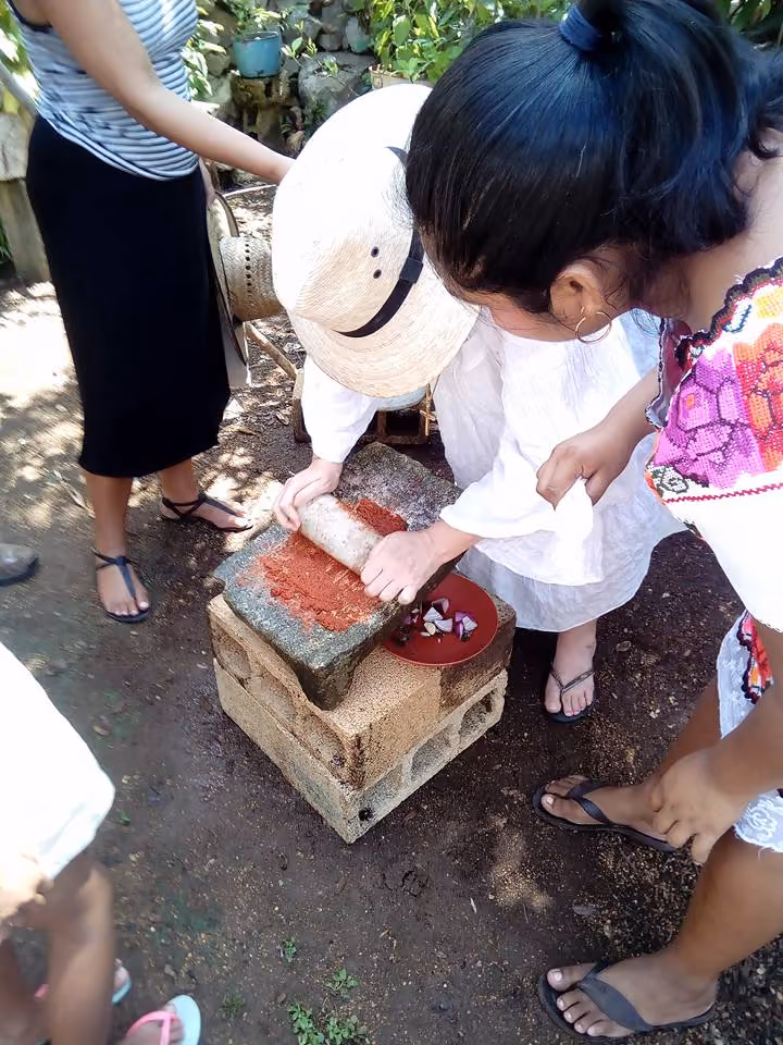 molido de especias en metate para la preparacion de cochinita pibil taller gastronomico en yaxunah