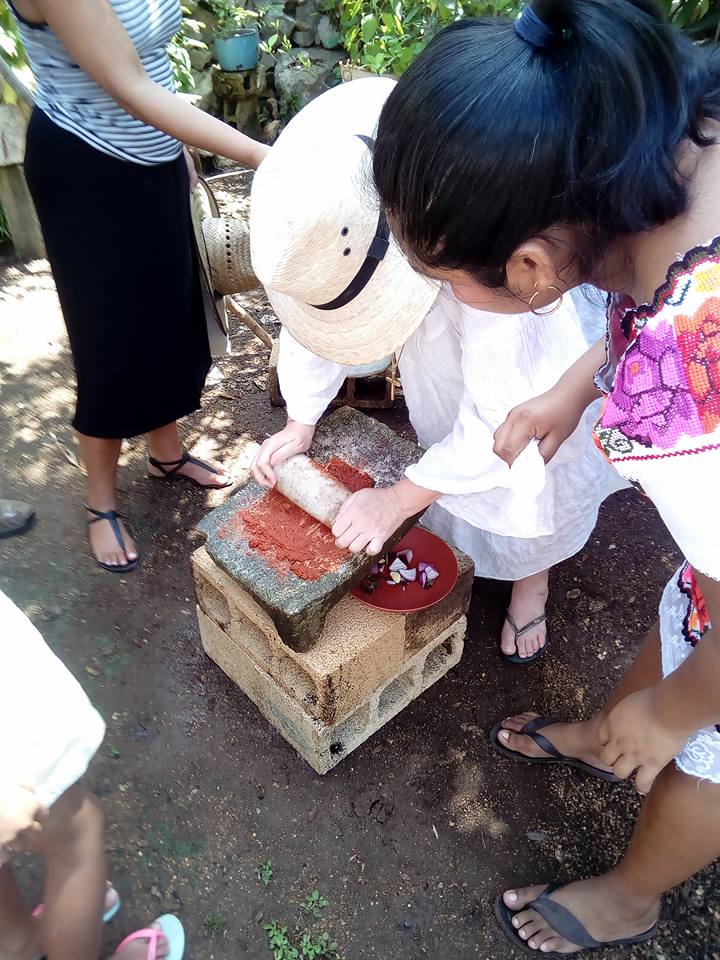 molido de especias en metate para la preparacion de cochinita pibil taller gastronomico en yaxunah