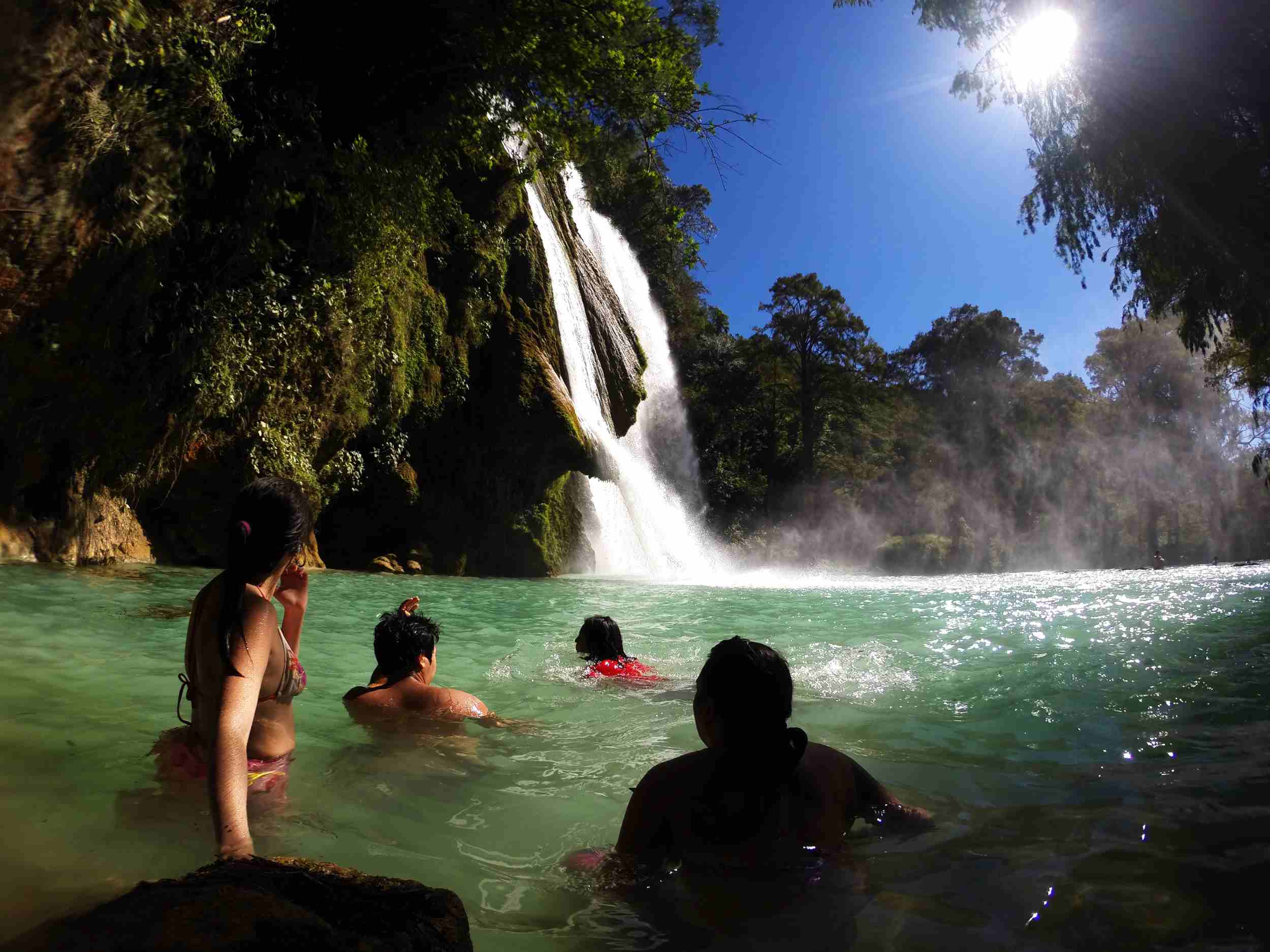 Turistas nadando en un río con una cascada