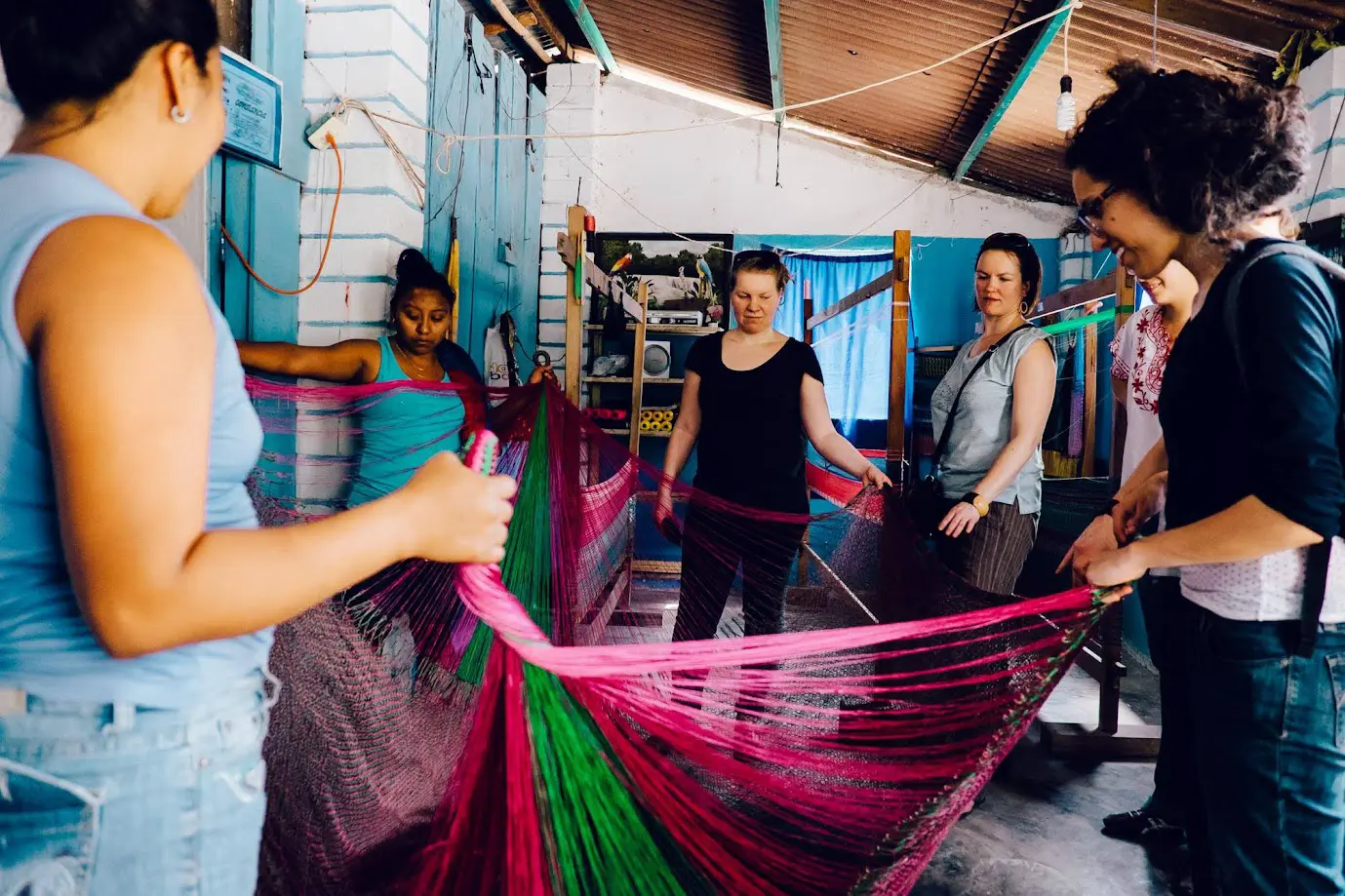 Mujeres de la comunidad y viajeros haciendo una hamaca artesanal