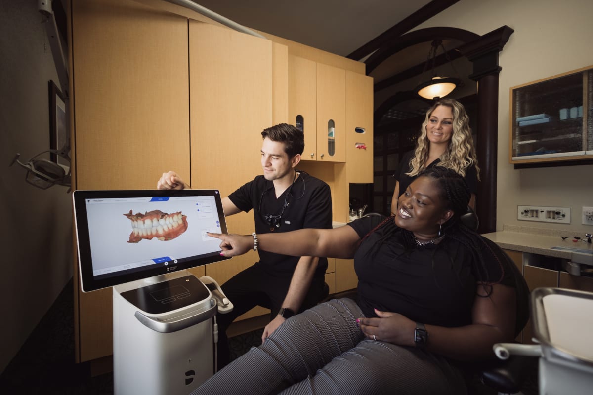 Dentist explaining dental crown procedure to patient using computer display