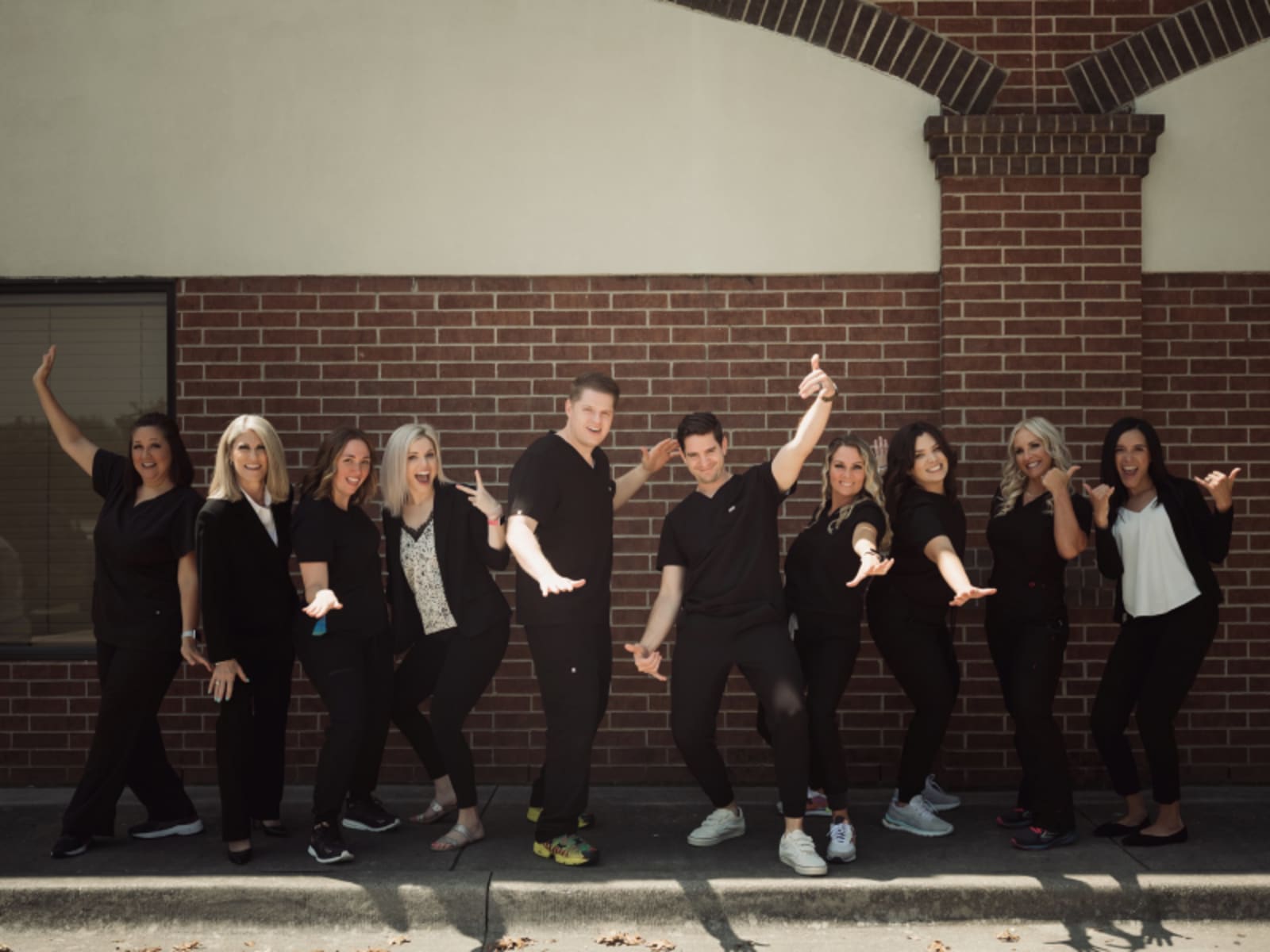 Titensor Dental team posing together in front of brick wall