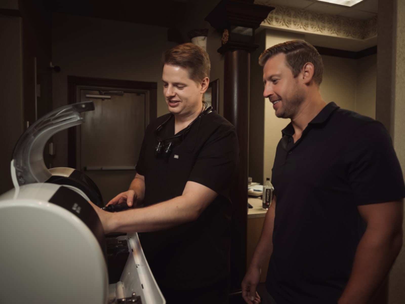 Two dental professionals examining dental equipment during crown procedure setup