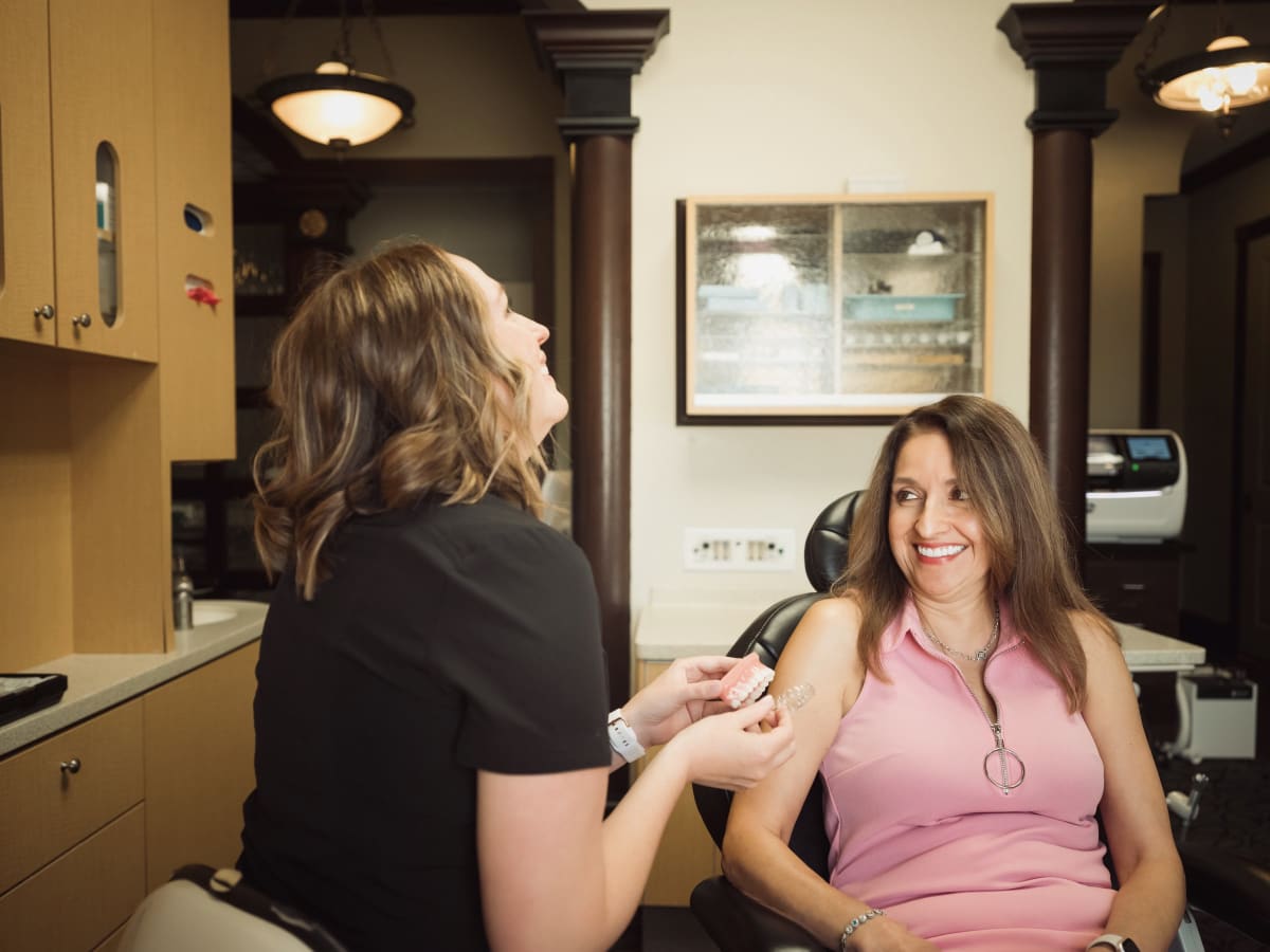 Dental professional examining a patient in treatment room with overhead lighting