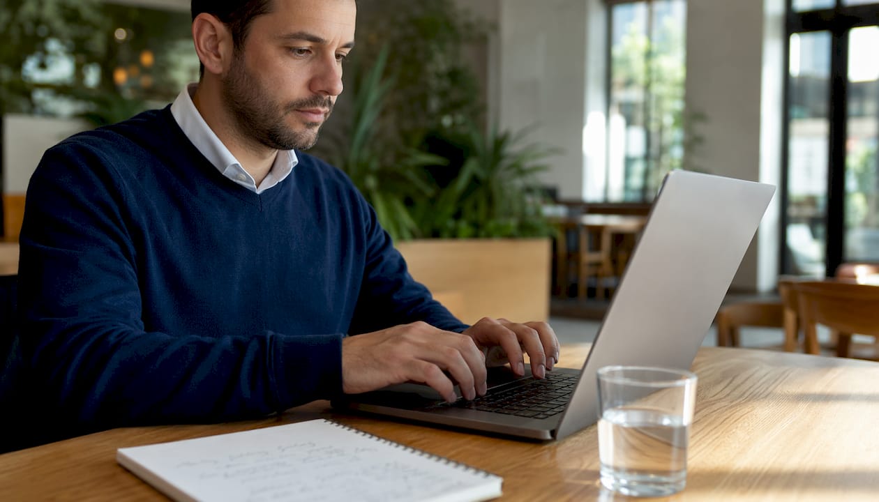Mãos digitando no teclado em um espaço de coworking