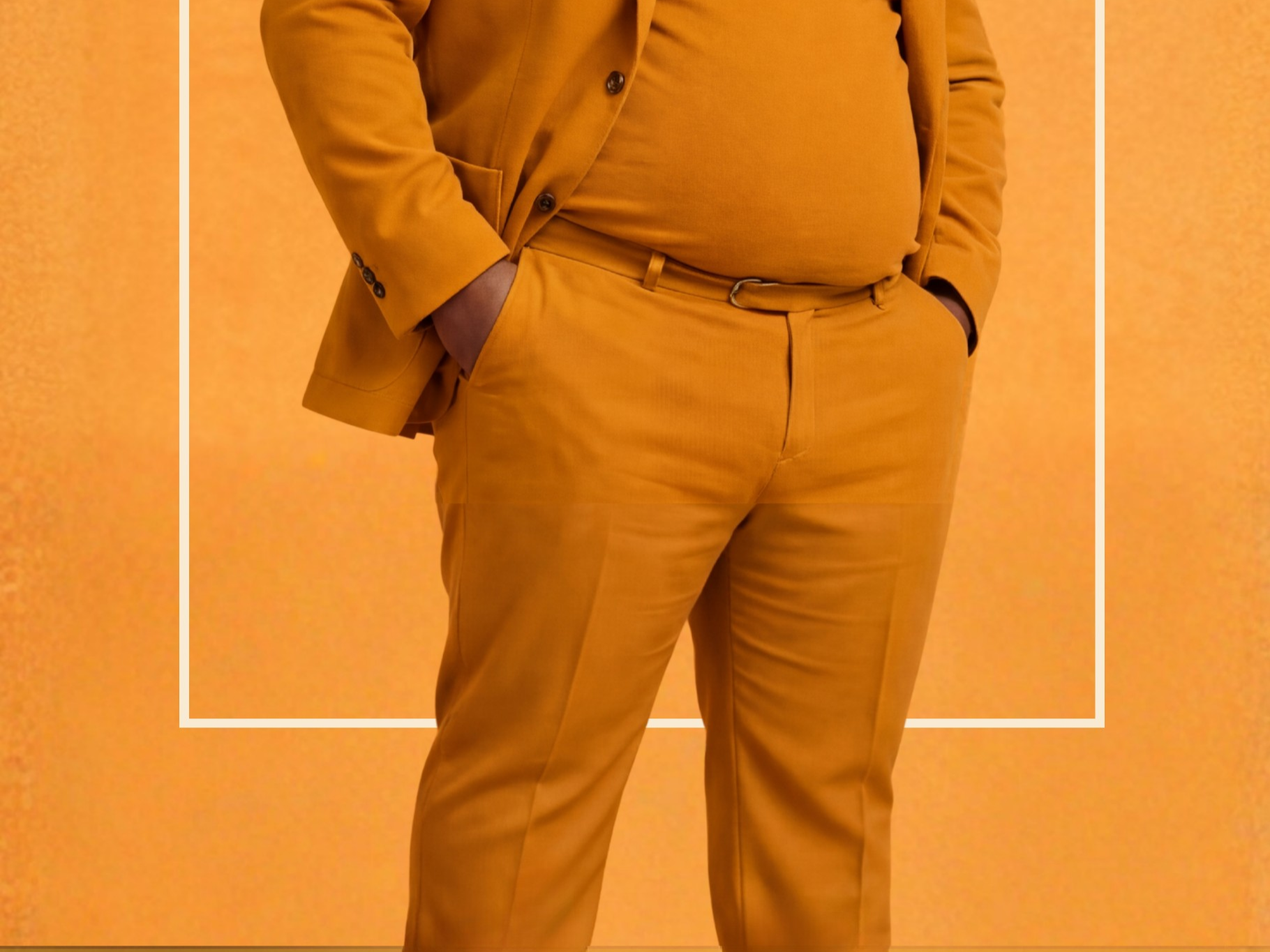 Cropped continuation of the same portrait showing the torso and waist of the person. The person’s hands are placed in the pockets of matching mustard-colored trousers. The jacket and turtleneck continue seamlessly from the image above. The background remains a consistent monochrome orange texture with a thin rectangular border visible near the edges of the frame.