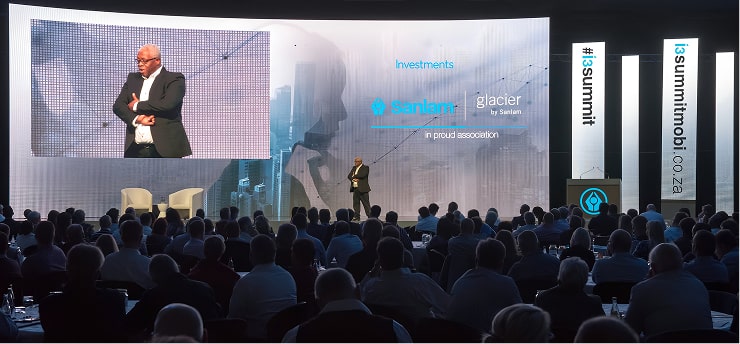 a man standing in front of a large screen with a large screen behind him