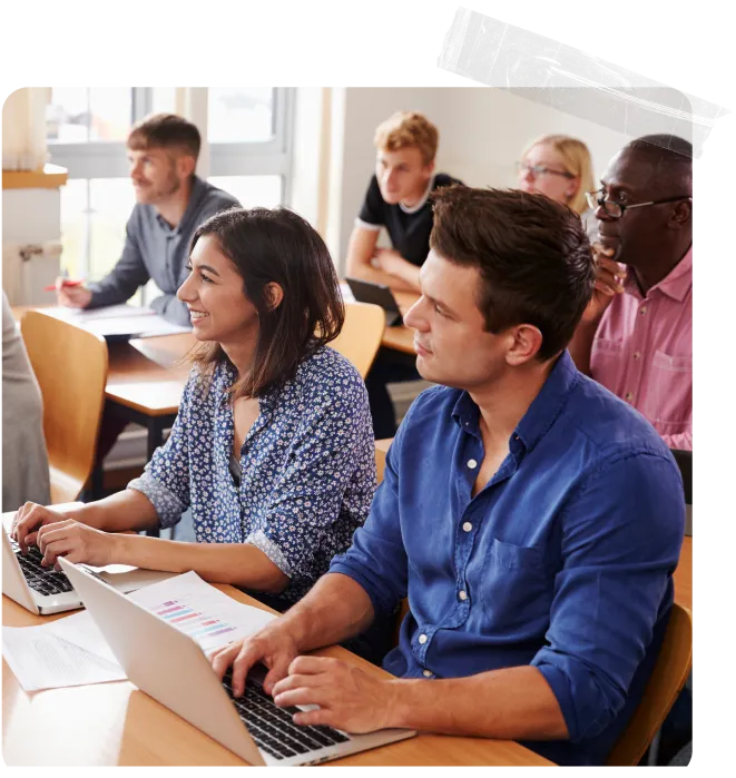 A group of people sitting at a table with laptops.