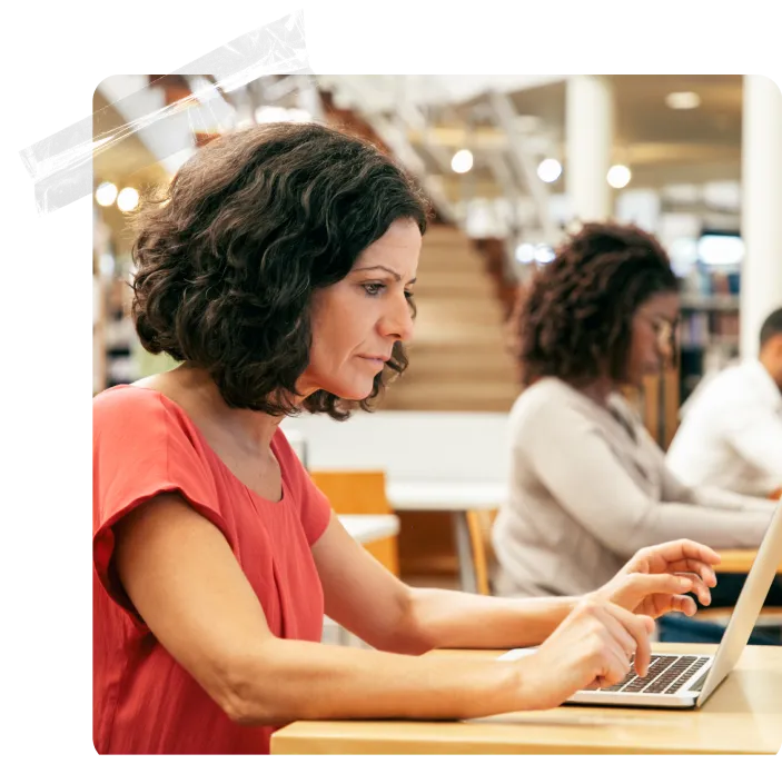 A group of people sitting at a table with laptops.