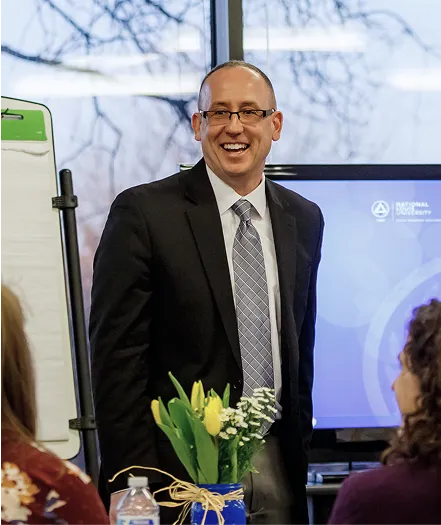 A man in a suit and tie standing in front of a tv.