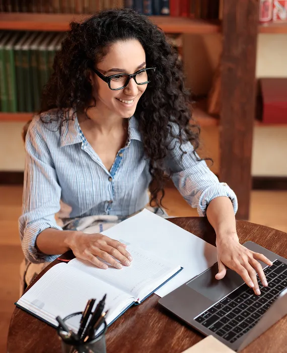 A woman sitting at a table working on a laptop.