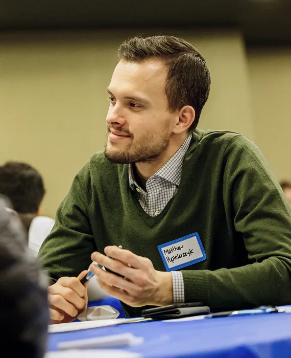 A man sitting at a table looking at his cell phone.