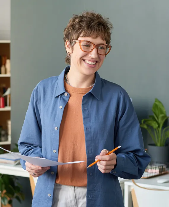 A woman holding a piece of paper and a pair of scissors.