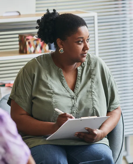 A woman sitting in a chair holding a clipboard.