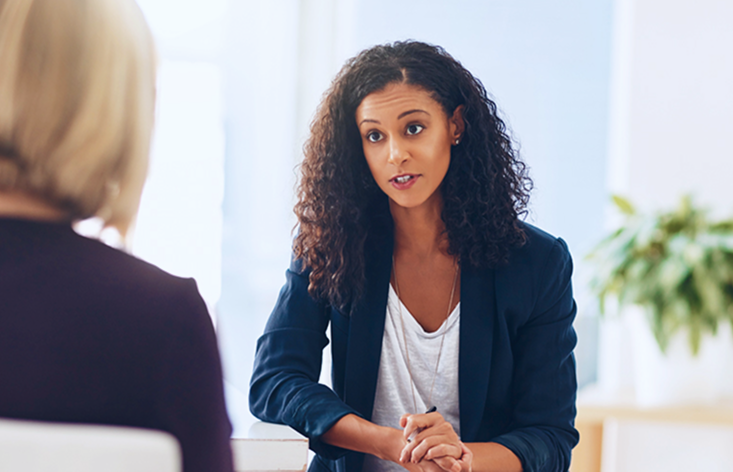 A woman sitting at a table talking to another woman.