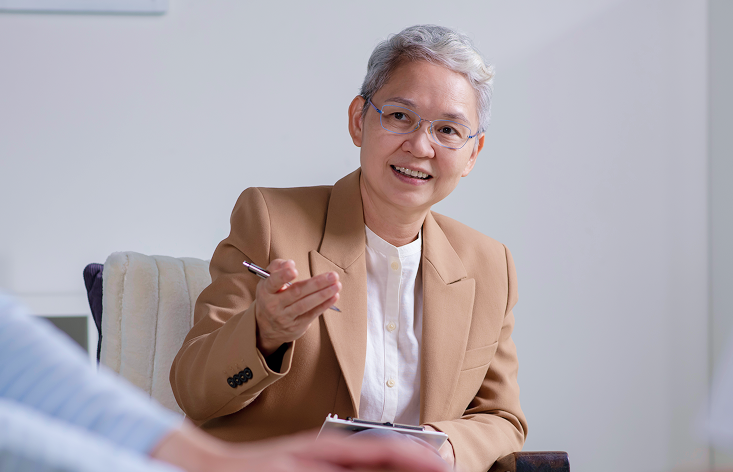 A woman sitting at a table with a pen in her hand.