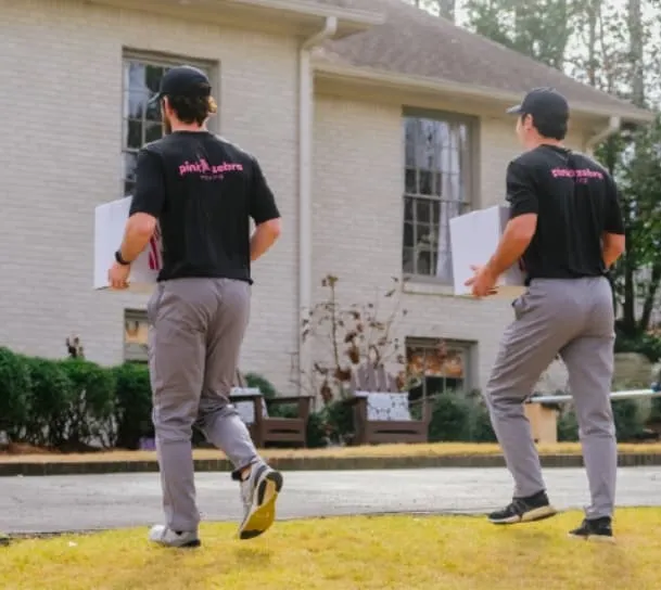 Pink Zebra movers carrying boxes to a house